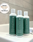 Vegan hair care set: trio of shampoo, conditioner, and treatment on bathtub with Natural Health Beauty Awards 2020 Shortlisted logo..