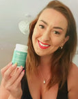 Smiling woman holding up Tint of Nature Rep-Hair Hair and Nail Supplements