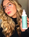 Smiling woman holding up Tints of Nature Seal and Shine Leave-in Conditioner showcasing gorgeous results.