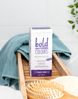 Box of Tints of Nature Bold Purple hair dye displayed in a bathroom with hairbrush and towel.