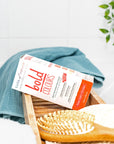 Box of Tints of Nature Bold rose Gold hair dye displayed in a bathroom with hairbrush and towel.