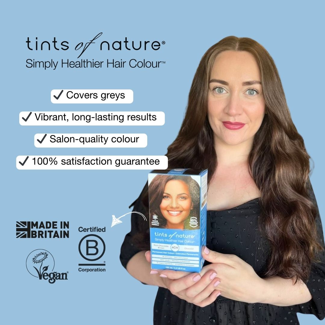 Happy woman holding Tints of Nature permanent hair dye carton with text on screen; covers greys, vibrant long-lasting results, salon-quality, 100% satisfaction guarantee